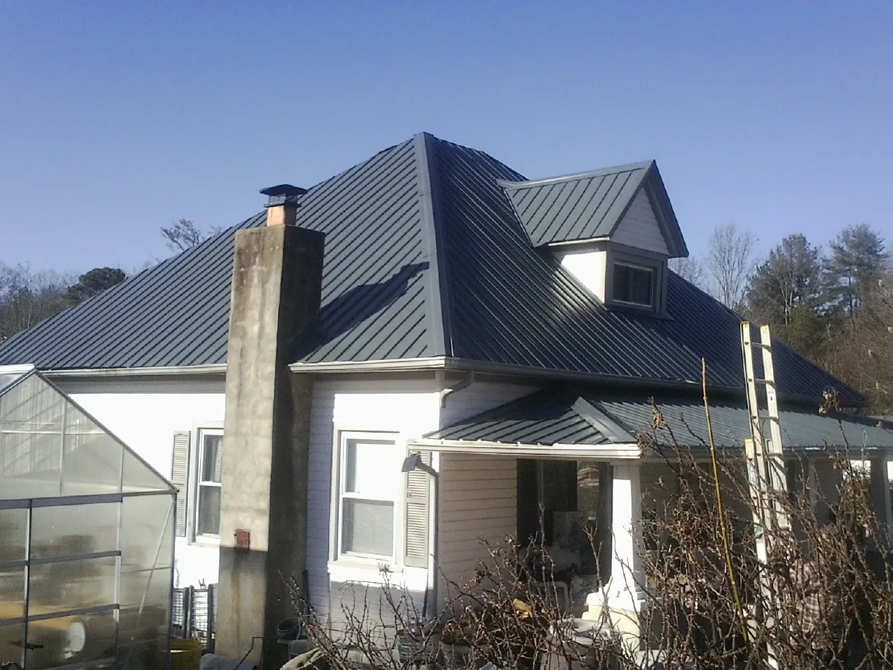Dark blue standing seam metal roof on a white farmhouse with dormer — Slate & Tile Roof Repair by Roofing Brothers in Sherborn