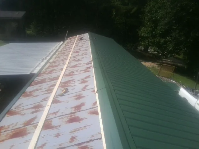 Old rusted panels beside newly installed green metal roofing — Wind Damage Roof Repair by Roofing Brothers in Sherborn
