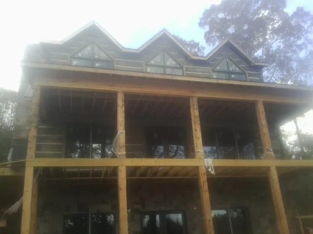 Dormers and porch framing on a large log home under construction — Roof Coating work by our crew in Sherborn
