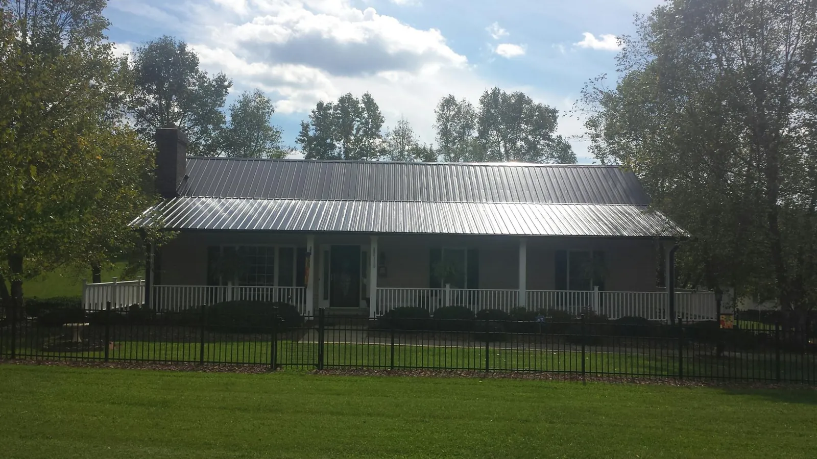 Gray metal roof on a brick ranch with a full width front porch — Gutter Guard Installation work by our crew in Sherborn