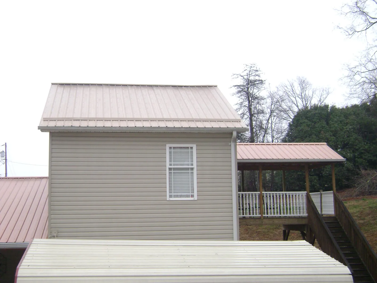 Tan metal roofs on a two story addition and attached porch, from a Roof Replacement job in Sherborn